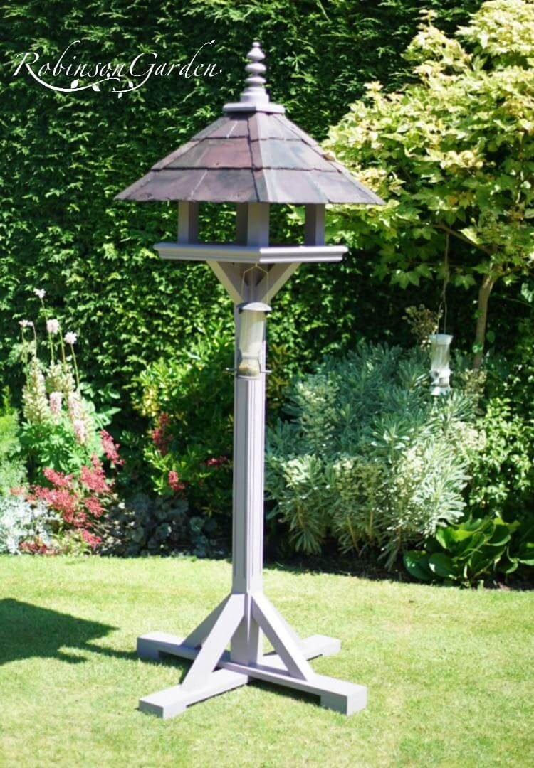 Bespoke bird table design with a slate roof hand painted in Lincolnshire, England, UK using Farrow & Ball exterior eggshell paint. Uniquely crafted using sustainable FSC certified timber / wood. This bird table and feeder is anti squirrel that doesn’t require anchoring pegs or to be attached to a fence. The bird table design is different to Argos, B&M, ALDI, homebase, dobbies, gardman, home bargains, pets at home, B&Q, b & q, M&S, Robert dyas, rspb, ikea, john lewis, QVC or any other garden centre. We are an online only store and we are not on the high street. We also have outlet shops across etsy and ebay UK. Our design plan, dimensions and height are suitable for small birds and is freestanding and a perfect bird table gift. Hooks provided to allow bird feeders to be hung from the bespoke bird feeders and table. Visit out gallery to see all the bird table images. Other options include bird table on pole or bird table on spike. Willow bird table on a tree stump option. Bird table / bird feeder delivered ready assembled. Perfect bird table for your garden.